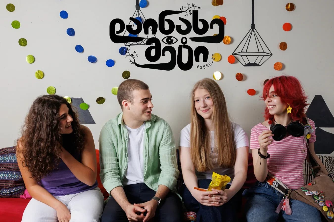 Four Letterato students on a bench under the Letterato wall logo