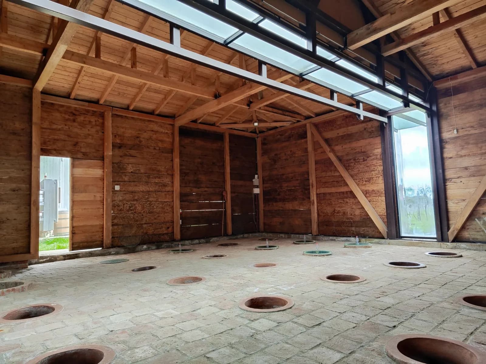Wine cellar with qvevri buried in a brick floor under a timber roof