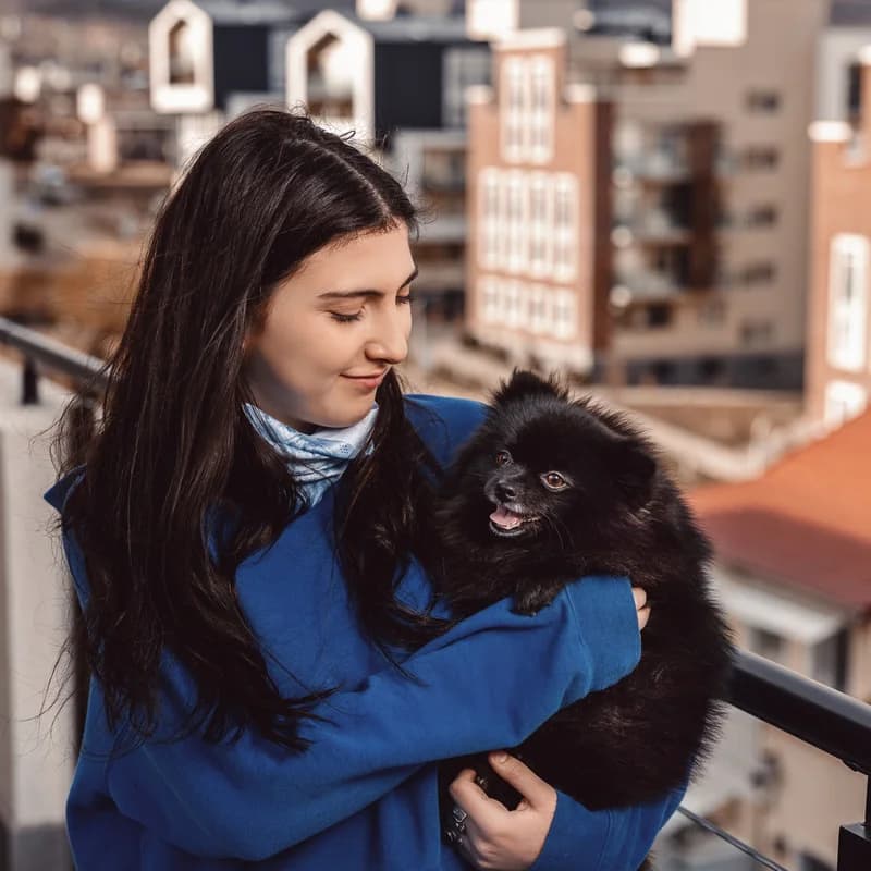 Pet food ad: woman with a black dog on a balcony